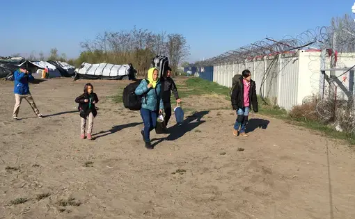 An Afghan family of four walks toward the Hungarian border to seek asylum. Under a controversial Hungarian policy that went into effect that day, they will be detained in a camp at the border while their case is decided. Image by Jeanne Carstensen. Hungary, 2017.