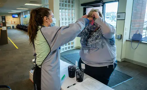 A staff member at Unity Care NW has her temperture checked and signs off on her lack of COVID-19 symptoms prior to beginning her shift at the clinic. Image by Gregg Brekke / Shutterstock. United States, 2020.