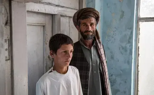Nawroz and his son Zewarshah at their home in Charkh, Aghanistan, in 2015. Nawroz had sent his sons out to collect grain on the morning of August 3 only to have Zewarshah witness the death of his younger brother, Ayman, whose nickname was Sufi. Image by Jason Motlagh. Afghanistan, 2015.