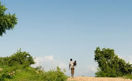 A woman walks with a child in the Omugo settlement for refugees who have fled from South Sudan to Uganda, June 27, 2019. Image by Adriane Ohanesian. Uganda, 2019.