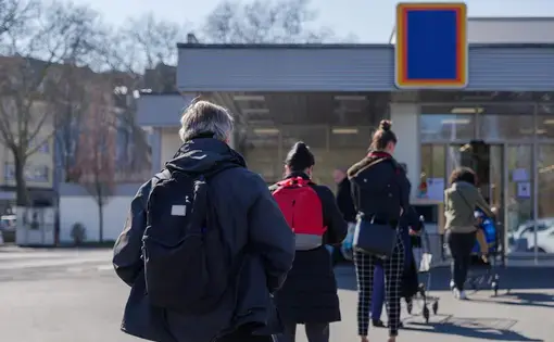 European people queue on street outside supermarket during quarantine for COVID-19 virus in Düsseldorf, Germany. Image by Peeradontax / Shutterstock. Germany, 2020.