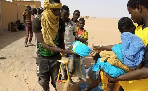 In this April 25, 2020 photo provided by IOM Niger, some of nearly 100 Nigeriens arrive in Assamaka, Niger, on foot from Algeria and now must be quarantined for two weeks at the remote Sahara border settlement, where water is scarce and midday temperatures reach over 110 degrees (45 degrees Celsius). Globally, coronavirus has marooned thousands of migrants in some of the world's harshest conditions on land and at sea. (IOM Niger via AP)