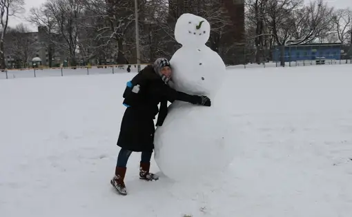 Raghda Altellawi hugs a snowman she discovers on her first day of school in Canada. Image by Robin Shulman. Canada, 2016. Raghda hugs a snowman