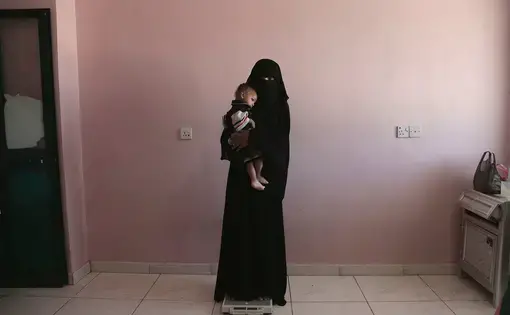 Umm Mizrah holds her baby Mizrah, in Aden, Yemen. Image by Nariman El-Mofty. Yemen, 2018.
