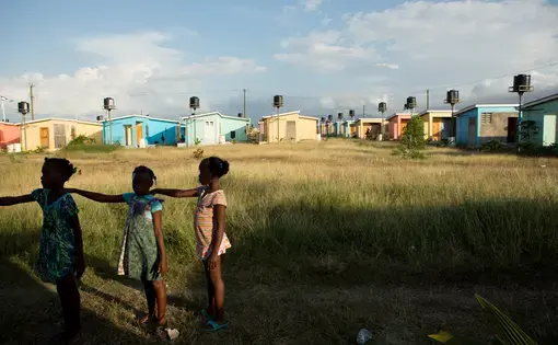 Third graders practice a marching drill after school with the help of their teacher Diendonne Daniel in preparation for a Flag Day ceremony to be held on May 18 in the village of La Difference in the north of Haiti, April 15, 2015. The USAID-funded housing project stands alone in the middle of grazing land near the Caracol Industrial Park. The project was initially projected to have 15,000 homes but so far consists of 900 one-bedroom lodgings of such poor quality that USAID has suspended contractors who built them. (photo by Allison Shelley) Media file: clintons_haiti_028.jpg