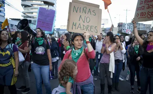 A woman hugs her daughter while holding a sign that says “Girls Not Mothers” in Quito, Ecuador. She marched with hundreds of women on March 8 for women's rights in Ecuador and around the world. Image by Dominique Riofrío. Ecuador, 2019.