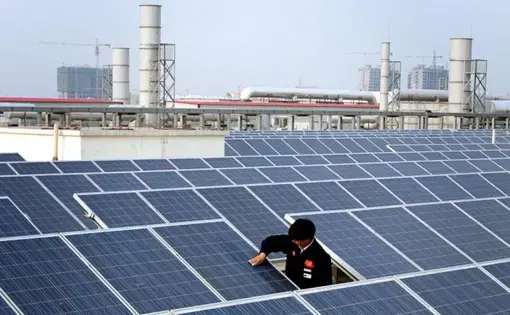 A worker cleans a solar panel on top of a factory building in Baoding City. China is installing a soccer field's worth of solar panels every hour. Image by Sean Gallagher. China, 2017. A worker cleans a solar panel on top of a factory building in Baoding City. China is installing a soccer field's worth of solar panels every hour. Image by Sean Gallagher. China, 2017.