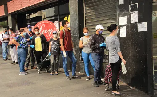 People wearing protective masks while waiting for turns to enter a supermarket during the COVID-19 pandemic in Caracas. Venezuela, 2020. Image by Edgloris Marys / Shutterstock. People wearing protective masks while waiting for turns to enter a supermarket during the COVID-19 pandemic in Caracas. Venezuela, 2020. Image by Edgloris Marys / Shutterstock.