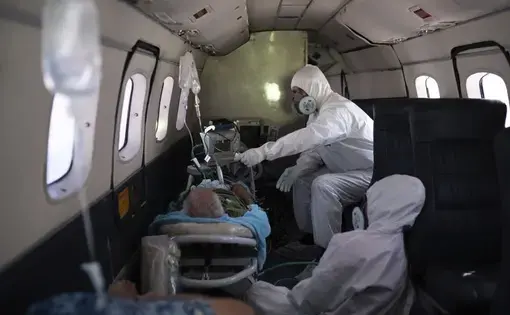Doctor Daniel Siqueira, top, and nurse Janete Vieira monitor 89-year-old COVID-19 patient Sildomar Castelo Branco onboard an aircraft, as he is transferred from Santo Antonio do Iça to a hospital in Manaus, Brazil, Tuesday, May 19, 2020. Image by AP Photo/Felipe Dana. Brazil, 2020.