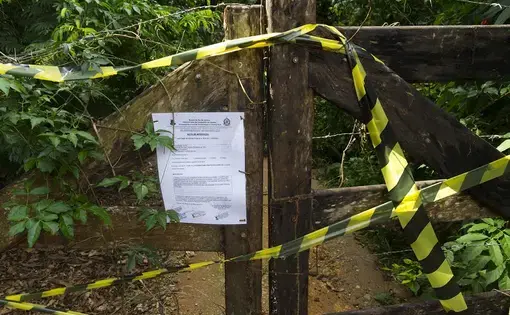 A notice posted to a gate in the village of Córrego da Luz, Brazil, lets visitors know that a trail leading to a waterfall is closed because mosquitoes carrying the yellow fever virus have been detected. The remains of a monkey that died of yellow fever was found near the trail. Image by Mark Hoffman. Brazil, 2017.
