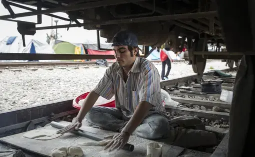 Syrian man bakes bread under train car