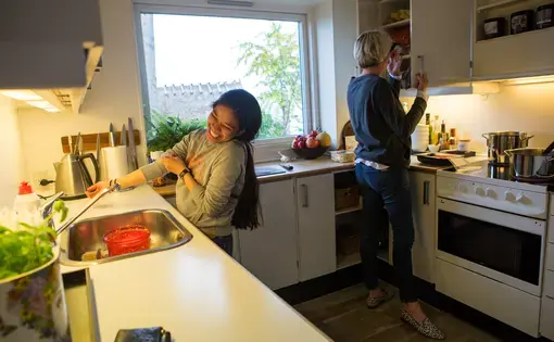 Jennifer D. Cuevas, left, helps Yvette Roepstorff, a fashion agent, make dinner at the Roepstorff home in the affluent suburb of Klampenbourg, where Cuevas works as an au pair, just north of Copenhagen, Denmark, May 21, 2016. Cuevas is the family's tenth au pair and will likely be the last. With new paperwork costs, insurance and monthly pay, the costs are far more then when the family hired their first au pair. "Also, my teenage daughter needs to learn the value of cleaning her own room," says Roepstorff. "For her, the party will soon be over." Image by Allison Shelley. Denmark, 2016. Jennifer D. Cuevas, left, helps Yvette Roepstorff, a fashion agent, make dinner at the Roepstorff home