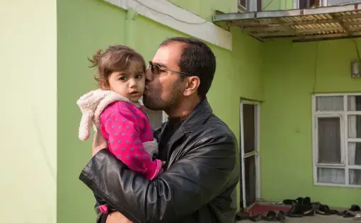 Dr. Wahid Qaderi kisses his daughter outside of his home in Kabul, Afghanistan. Dr. Qaderi talks about his family's decision to leave Afghanistan in the film "Afghanistan by Choice." Image by Alexandria Bombach. Afghanistan, 2016. Afghanistan by Choice