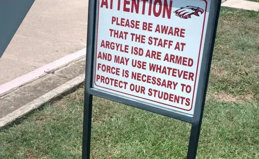 Sign warns that there are armed staff members at Texas school. Image by Spike Johnson. United States, 2018.