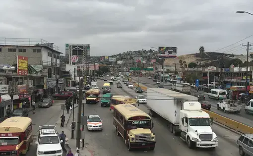 A footbridge offers an overview of Tijuana’s public transit options: garishly painted ex-school buses, collective taxi vans, and individual taxis all jockeying for space. Image by Patrick Reilly. Mexico, 2017.