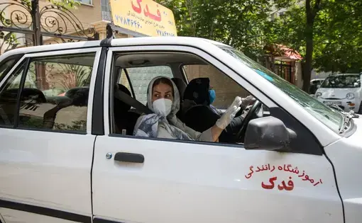 Maryam Rezaie, 58, works as a driving instructor in the capital Tehran and supports her family financially. But wearing a mask and gloves along with the headscarf is an additional limitation in the car. Maryam is afraid of getting infected at work. Image by Mehdi Fazlollahi / NVP Images. Iran, 2020.