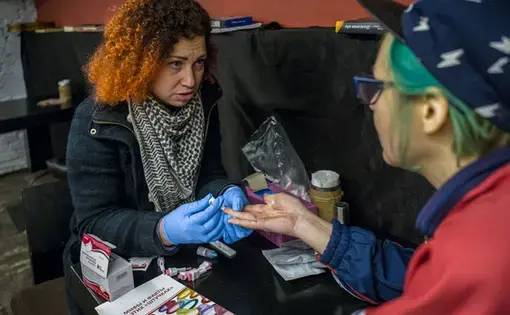 Maria Jacovleva (left), who directs the nongovernmental organization Candle, does HIV testing at a St. Petersburg vegan bar, Animal. Image by Misha Friedman. Russia, 2018.