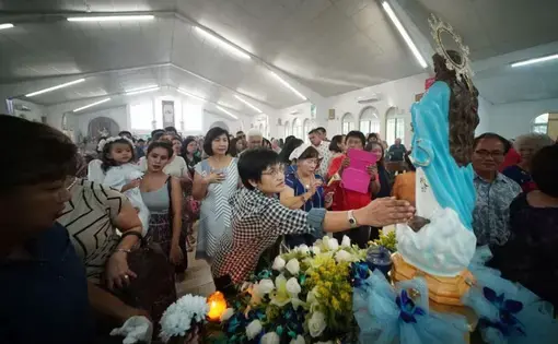 Parishioners pay their respects during a Mass held in honor of the Assumption of Our Lady in Piti, Guam. Image by Cory Lum. Guam, 2017.