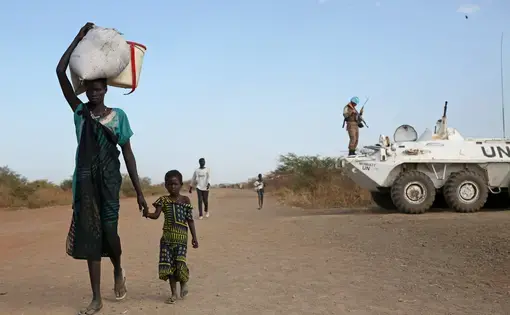 Internally displaced South Sudanese walk past a U.N. peacekeeper in Bentiu. Image by Cassandra Vinograd. South Sudan, 2016.