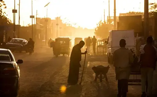 A man sweeps dust off the street at dusk in Agadez, Niger. Image by Joe Penney. Niger, 2018.&nbsp;