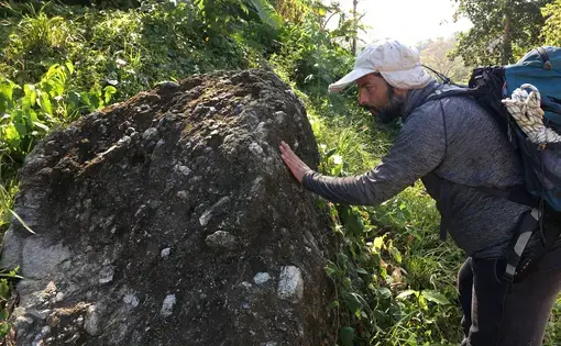 Geologist Felipe Lamus Ochoa examines a volcanic rock near the Gulf of Urabá in northern Colombia. Image by Lizzie Wade. Colombia, 2018.