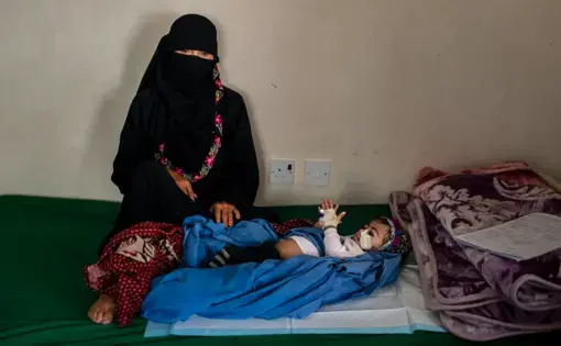Kafaya, whose name means “enough,” lies next to her mother on May 7, 2018, in Bani Mansur, Yemen. Image by Alex Potter. Yemen, 2018.