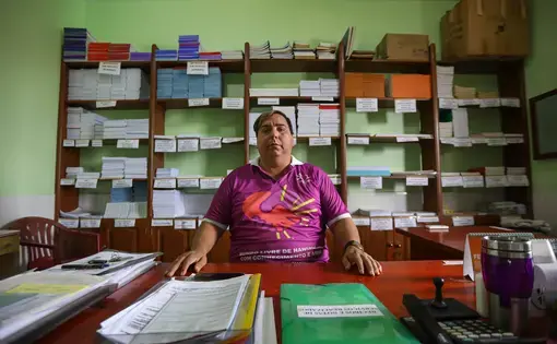 Edmilison Picanco, president of MOHAN in Pará, sits at his desk at the Center of Dermatology in Marituba. As the son of two leprosy patients, Picanco is leading the campaign demanding federal reparations for the children of these patients. Image by Anton L. Delgado. Brazil, 2020.