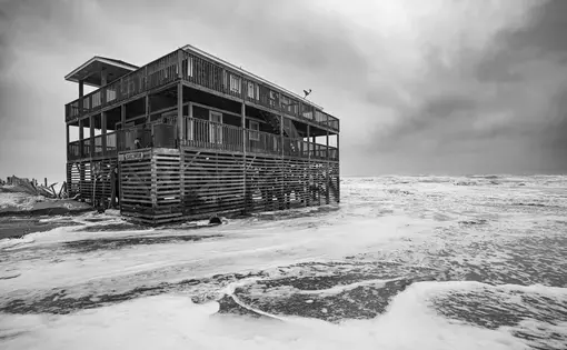 Surf washes around an Outer Banks home during a nor’easter in November 2019. Image by Jared Lloyd. United States, 2019.