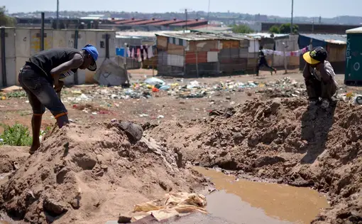 A small-scale miner processes gold ore by hand in an informal settlement in Johannesburg. Image by Mark Olalde. South Africa, 2017.