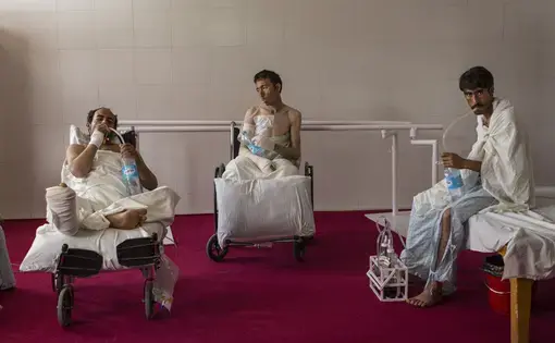 Patients with chest injuries strengthen their lung capacity with water bottles in the physical therapy room at the Emergency hospital in Lashkar Gah, Afghanistan. Image by Paula Bronstein. Afghanistan, 2015.