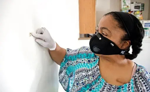 Kim Daniel shows where a bullet fired from a nearby apartment entered her unit. Image by Wiley Price/St. Louis American. United States, 2020.