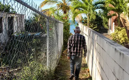 Ismael Guadalupe Ortiz walks between buildings to the beach around the Bravos de Boston neighborhood, where vacation homes, small hotels and Airbnbs proliferate. Image by Kari Lydersen. Puerto Rico, 2019.