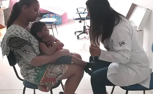 Dr. Isabella Santana, an ophthalmologist at the Altino Ventura Foundation in Recife, Pernambuco, conducts a visual exam with Pedro, a young child born with microcephaly associated with Zika virus, while his mother Juliana holds him. To date, the Altino Ventura Foundation has diagnosed 322 babies with congenital Zika syndrome. Image by Poonam Daryani. Brazil, 2017.