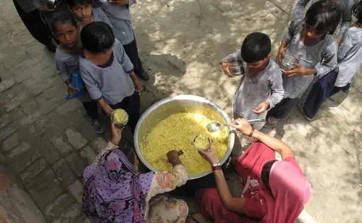 Santosh (left) and Suman (right), the two school cooks, serve the khichdi to girls during lunch time. Image by Rhitu Chatterjee. India, 2014. Media file: mdm_show4.jpg