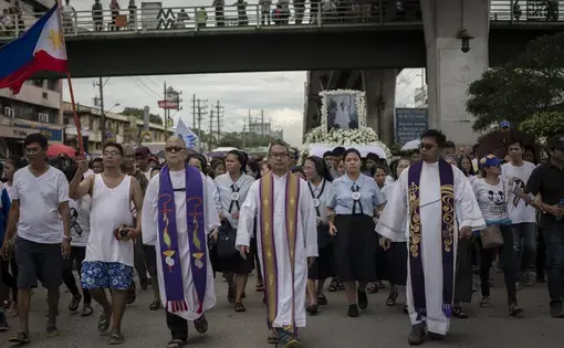 Catholic priests Robert Reyes (left) and Flavie Villanueva (center) lead the funeral procession of seventeen-year-old Kian Loyd delos Santos, who was shot and killed by police. Image by Eloisa Lopez. Manila, 2017.