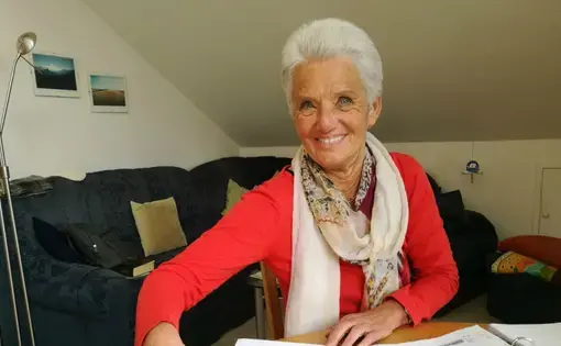 Christa Schmidt is pictured at the table in her apartment in Traunreut, where she tutors refugees in German. Schmidt’s parents were German refugees from Romania. Image by Frank Hessenland. Germany, 2017.