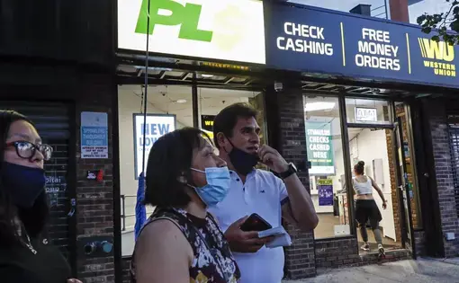 Magnolia Ortega, center, stands outside a Western Union with her husband Arturo Morales and their daughter Marlene after wiring money to her family in Mexico, Wednesday, June 24, 2020, in Staten Island, New York. Ortega lost her job cleaning houses amid the COVID-19 pandemic, reducing the monthly amount she sends home. She's considering returning to her hometown of San Jeronimo Xayacatlan but says there's no work there either and that would mean one less family member sending back one less monthly check…