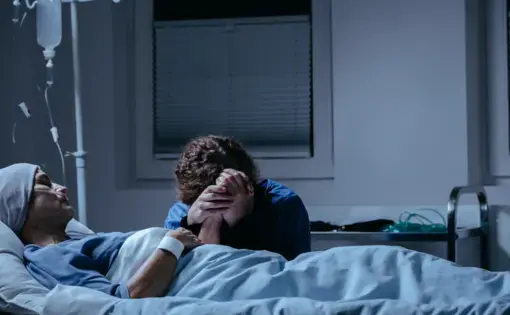 Daughter crying at her dying mother's bed in the hospital. Image by Shutterstock.