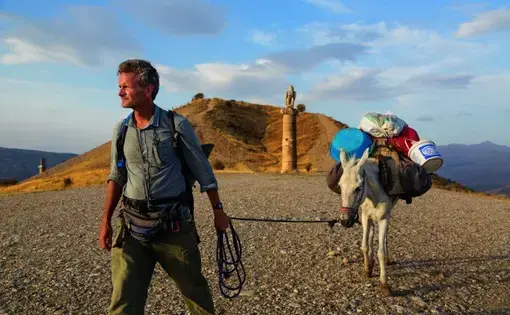 In eastern Turkey, Paul Salopek leads his mule past the Karakuş royal tomb, built in the first century B.C. by one of the area’s many ruling states. When Syrians began to pour over the border 70 miles to the south, he and photographer John Stanmeyer drove down separately to report on the situation. Image by by John Stanmeyer/National Geographic.