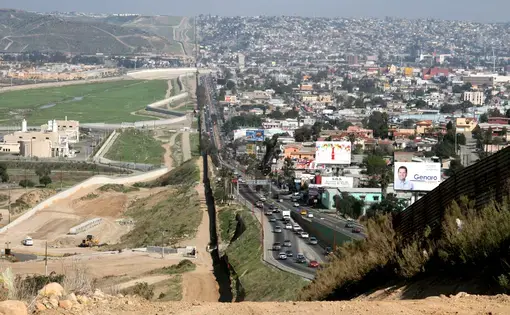 A small fence separates densely-populated Tijuana, Mexico, right, from the United States in the Border Patrol's San Diego Sector. Image by Sgt. 1st Class Gordon Hyde / United States Army. United States, 2007.