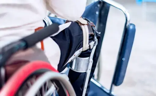 A man sitting on the wheelchair with an old polio knee brace, closeup view. Image by Ruchuda Boonplien / Shutterstock. Undated.