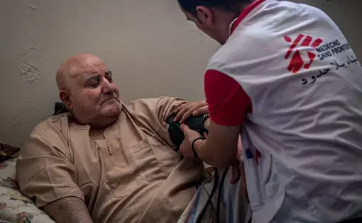 A physician checks on Ibrahim Hassan (left), who lives as a displaced person in Jordan after fleeing the regime in Syria. Image by Neil Brandvold. Jordan, 2017.