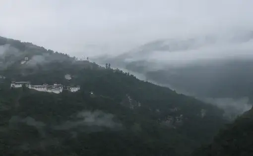 The Trongsa Dzong, or fortress, sits nestled among the trees in the early morning mist in the district of Trongsa. Image by Emma Johnson. Bhutan, 2019.