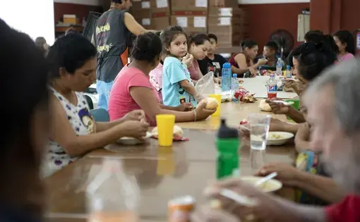 A young girl stands on a chair in the dining hall at Casa Indi in Monterrey, Nuevo Leon on Aug. 5, 2019. The Mexican government has been busing migrants away from the border and into the interior of the country. Image by Miguel Gutierrez Jr. Mexico, 2019.
