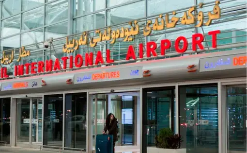 With a four-foot, two-pronged, gold sword in her suitcase, Zahra Ahmad walks toward security at Erbil International Airport in Erbil, Iraqi-Kurdistan on Saturday, Feb. 16, 2019. Ahmad received the sword when she visited her family for the first time in Baghdad. The sword is called Zulfiqar or Imam Ali ibn Abi Talib's sword. The sword made it through the airports of Baghdad, Erbil, Turkey, Amsterdam, Iceland and Detroit. Image by Brontë Wittpenn. Iraq, 2019.