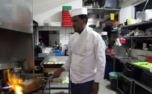 In this Wednesday, Aug. 8, 2018 photo, Eritrean migrant Russom Weldu Weldeslasie works at a restaurant in Tel Aviv, Israel. African migrants coming into Israel have been detained, threatened with deportation, and faced hostility from lawmakers and residents. Now, they face another burden: a de facto 20 percent salary cut that has squeezed them financially and driven them further into poverty. Image by Caron Creighton. Israel, 2017.