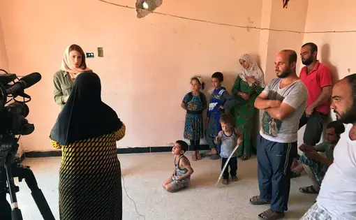 A Syrian family watches as Gayle Tzemach Lemmon conducts an interview. Image by Jon Gerberg/PBS NewsHour. Syria, 2017.