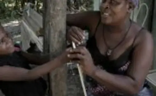 Belange, Haiti—August 3, 2018—Paula Paul (right) with her daughter, six year-old Marie Stacy (left) in front of their home in Belange, Haiti. Paula Paul has been diagnosed with cervical cancer. She has been undergoing treatment for the disease but due to lack of funds, has been thinking about not making the trips to the hospital in Mirebalais where she gets her chemotherapy. Image by José Antonio Iglesias. Haiti, 2018. 