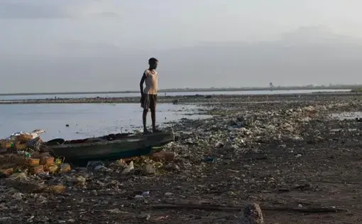 A young girl stands on the bow of a fishing boat docked on the shoreline of Cité Soleil. Image by Meghan Dhaliwal. Haiti, 2012.