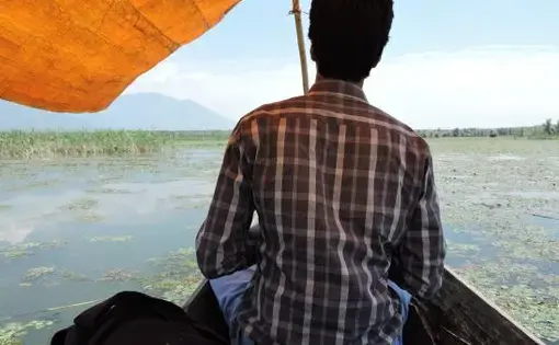 Dr. Ather Masoodi is on the lookout for alligator weed in Wular Lake, the dangerous invasive plant species that can overrun other beneficial aquatic plants and fauna. He is frustrated with the lack of action and planning against alligator weed and other non-native species. Image by Reana Thomas. India, 2014. Media file: wular_lake_june_25th_85.jpg